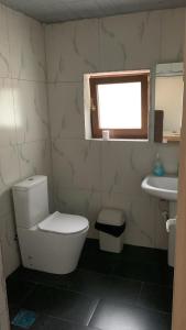 a bathroom with a toilet and a sink and a window at Natura Koman in Koman