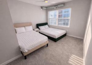 a small room with two beds and a window at Olive Oasis in Des Moines