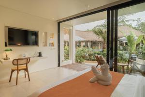 a stuffed bunny sitting on a bed in a room with sliding glass doors at Hotel Together Bali in Uluwatu
