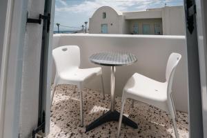 a table and two white chairs on a balcony at Kamarela Studios in Kamari +39 photos