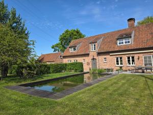 a house with a pond in the yard at B & B Victors Hof, met zwemvijver en leuke diertjes in Lievegem
