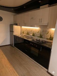 a kitchen with black appliances and white cabinets at Затишні апартаменти Східна Перлина in Vinnytsya