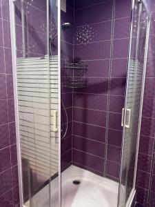 a purple bathroom with a shower with a glass door at Затишні апартаменти Східна Перлина in Vinnytsya
