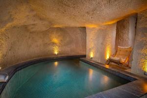a swimming pool in a cave with a chair in it at Cappa Via Cave Hotel in Ürgüp