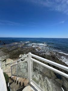 a white fence on the rocks near the ocean at Hotel Ariana in Marine du Miomo