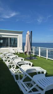 a row of lawn chairs and umbrellas on a balcony at Hotel Ariana in Marine du Miomo