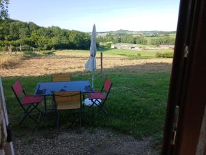 a table and chairs with an umbrella in the grass at Gite de Labarraque in Monbahus