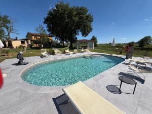 a large swimming pool with chairs at Agriturismo Podere Delle Querci in Castiglion Fiorentino
