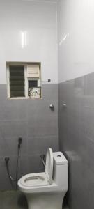a bathroom with a white toilet and a window at Hotel KGR in Palni