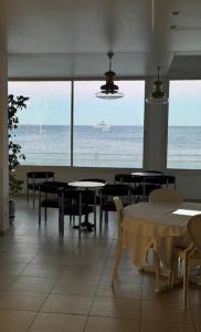 a restaurant with tables and chairs and a view of the ocean at Hotel Ariana in Marine du Miomo
