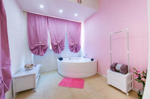 a bathroom with a large tub and pink curtains at Le corti di Elena Martina in Miggiano +12 photos