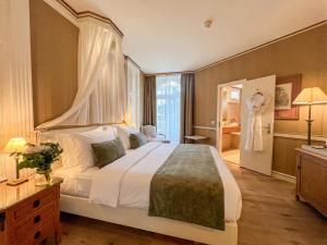 a bedroom with a large white bed and a bathroom at Carlton Lausanne Boutique Hôtel in Lausanne +31 photos