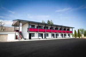 a large white building with red balconies and a parking lot at Burg Rooms - 24h Self-Check-in in Spielberg