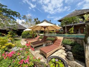 a patio with benches and an umbrella next to a pool at Hotel Bunga Permai in Ubud