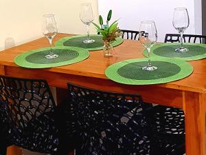 a wooden table with four green plates and wine glasses at Nosso Cantinho no interior in Lençóis