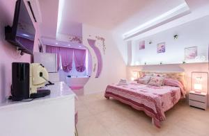 a pink bedroom with a bed and a tv at Le corti di Elena Martina in Miggiano