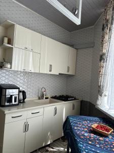 a kitchen with white cabinets and a sink and a table at Batumi in Stantsiya Batumi-Passazhirskaya