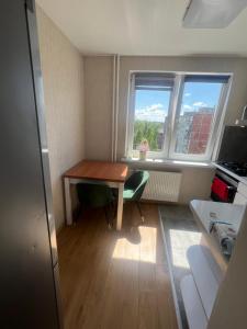 a small room with a wooden table and two windows at Deividas apart in Vilnius