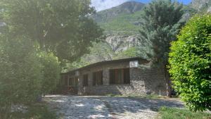 a small brick house with mountains in the background at Natura Koman in Koman