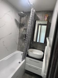 a bathroom with a tub and a sink and a mirror at Deividas apart in Vilnius