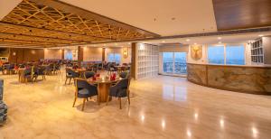 a dining room with tables and chairs and windows at Hibiscus Elite Hotel in Greater Noida