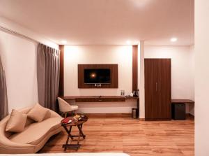 a living room with a couch and a tv at Hibiscus Elite Hotel in Greater Noida