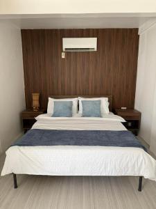 ein Schlafzimmer mit einem großen Bett und blauen Kissen in der Unterkunft The Beachfront Bataan in Morong