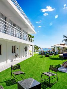 ein Rasen mit Stühlen und Tischen in einem Haus in der Unterkunft The Beachfront Bataan in Morong