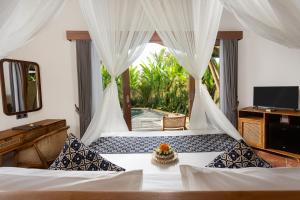 a bedroom with a bed with a mirror and a television at The Scape Valley Villas in Tampaksiring +36 photos