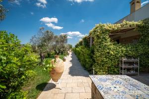 a garden path with a large vase and bushes at Tenuta Cesarina in Alessano