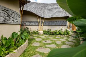 a garden with a stone walkway next to a building at The Scape Valley Villas in Tampaksiring
