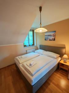 a bedroom with a large bed with white sheets at Hotel Kärntnerhof Velden - Zum Schankbaron in Velden am Wörthersee
