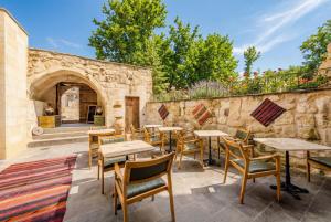 a patio with tables and chairs and a stone wall at Cappa Via Cave Hotel in Ürgüp