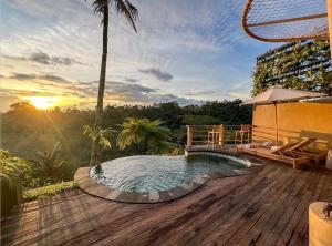 a pool on the deck of a house with the sunset at The Scape Valley Villas in Tampaksiring
