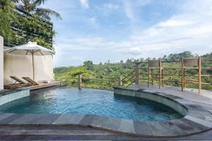 a plunge pool with an umbrella and a wooden deck at The Scape Valley Villas in Tampaksiring