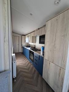 a kitchen with blue cabinets and a counter top at Three Lochs Holiday Park, 139 Loch View with Lazy Spa Hot Tub, Platinum 3 bedroom Holiday Home for Hire in Balminnoch