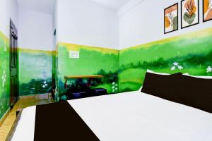 a bedroom with a white bed and a green wall at Hotel O A Star Lodge in Trichūr