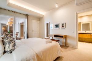 a white bedroom with a bed and a piano at CICAS VILLA in Albufeira