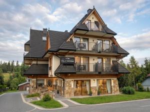 a large wooden house with a black roof at Golden Apartments - Villa Taternik - Tatry View in Zakopane