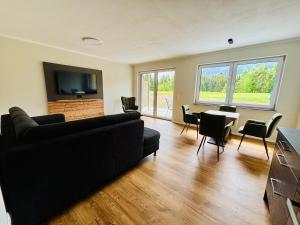 a living room with a black couch and a table at Hotel Nesselwanger Hof in Nesselwang