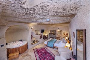 a bedroom with a large bed and a tub in a cave at Cappa Via Cave Hotel in Ürgüp