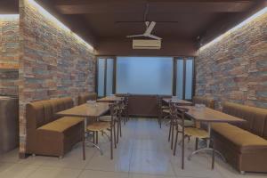 a restaurant with tables and chairs and a brick wall at Hotel Shrimmaya, Ujjain in Ujjain