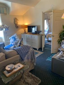 a living room with a couch and a tv in it at The Suites At Ty Anne in Beaumaris