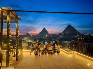 a group of people sitting on a balcony with pyramids in the background at Pyramids Spiritual Hotel in Cairo