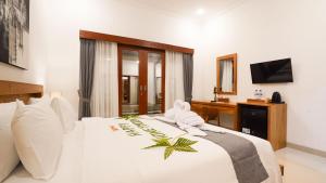 a bedroom with a large white bed with a television at Royal Crown Villas in Ungasan