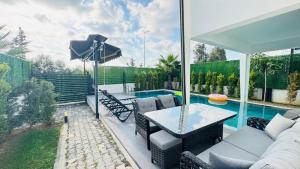 a patio with a table and chairs and a pool at Villa Marcy in Belek