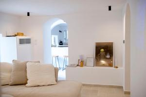 a white living room with a couch and a kitchen at Casa Amore in Ermoupoli