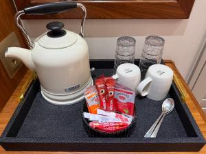 a black tray with a tea kettle and some drinks at Be Our Guest Accommodation in Klerksdorp