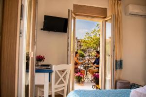 a room with a balcony with two people sitting at a table at INAH Rooms in Dorgali
