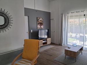 a living room with a yellow chair and a television at maison de campagne in Bazillac